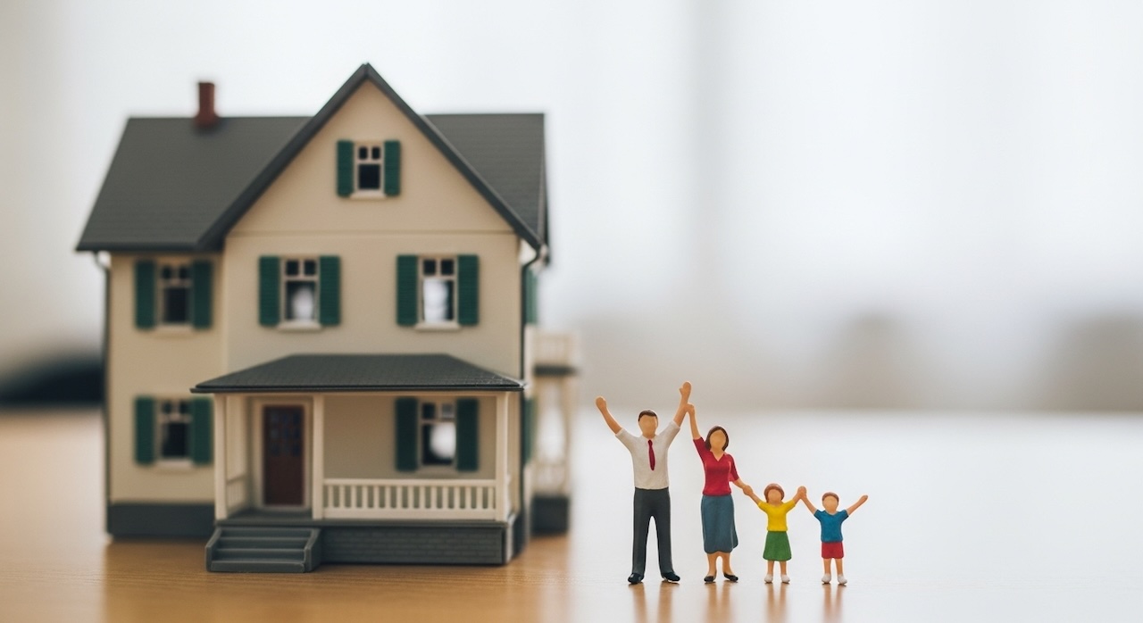 家の模型の前で手を挙げる家族のフィギュア
