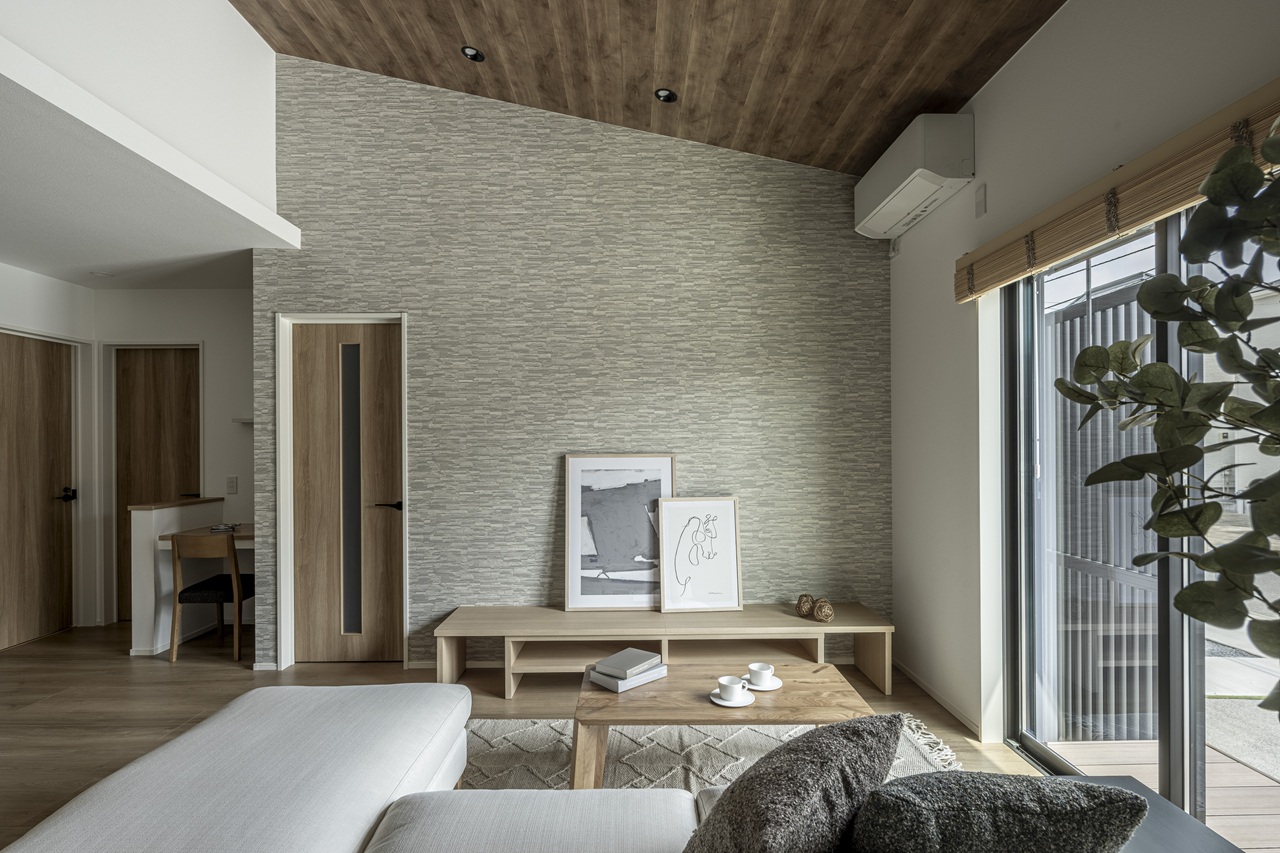 木目天井とアクセント壁が映える、自然光の入るシンプルで落ち着いたリビング空間