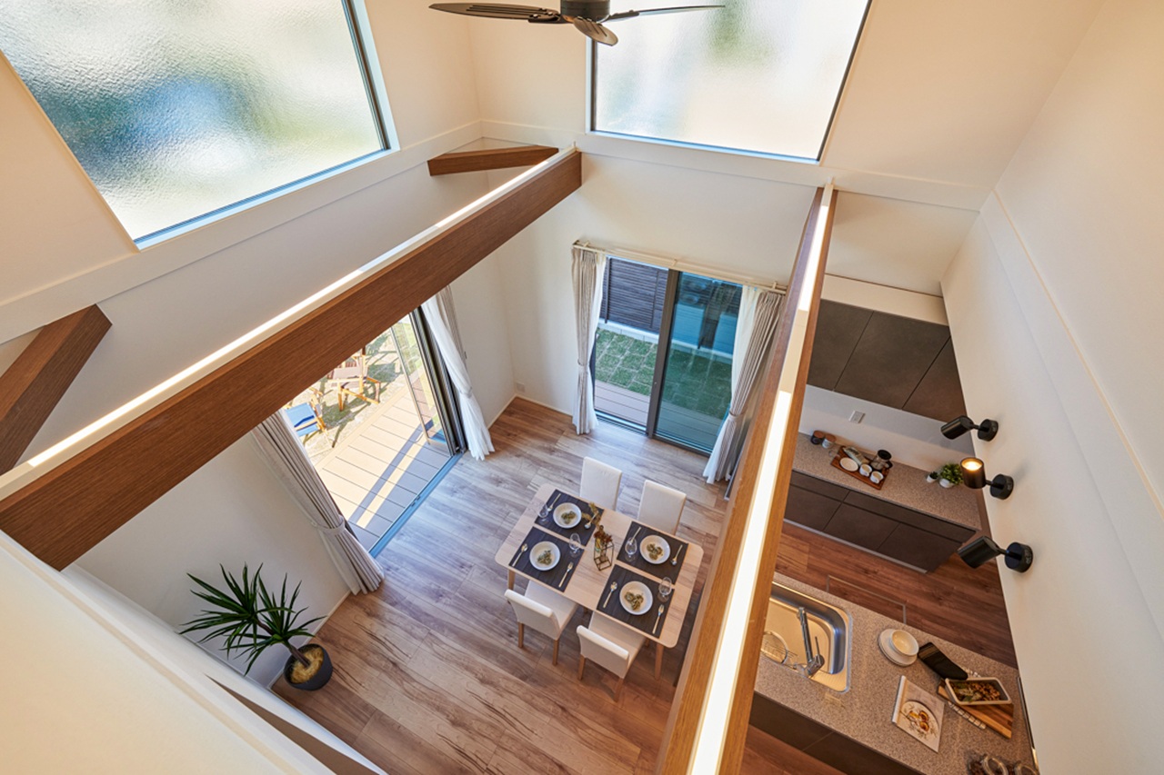 吹き抜け上部から見下ろした、ダイニングとキッチンが明るくつながる開放的な室内空間