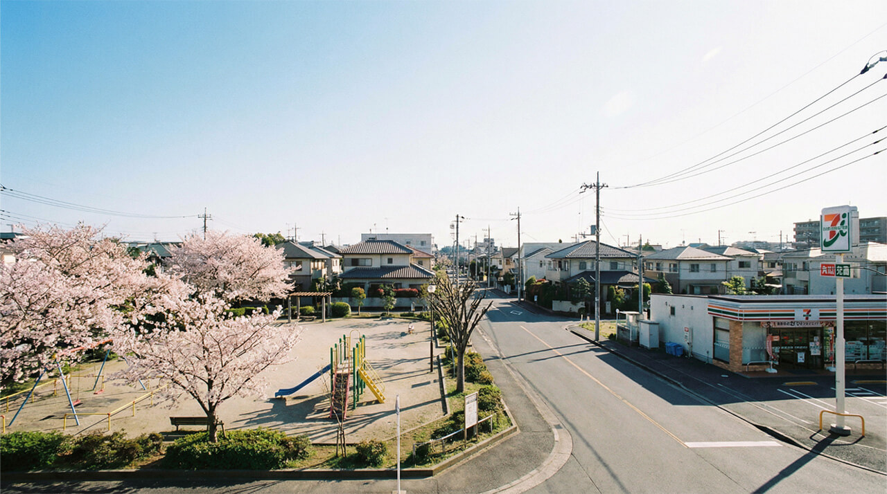 桜が咲く公園とコンビニが隣接する静かな住宅街の様子